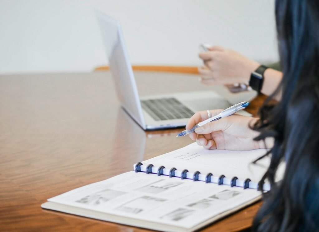 Two people working with a laptop and notes - bookkeeping and payroll planning