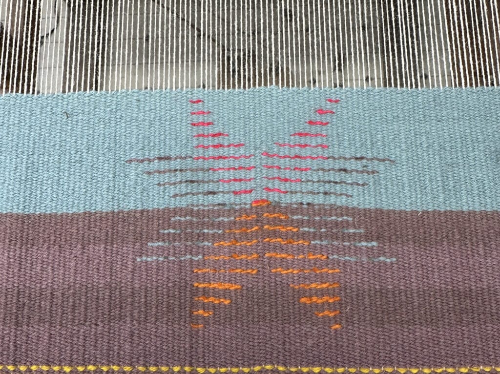 a woven piece on the loom featuring a star