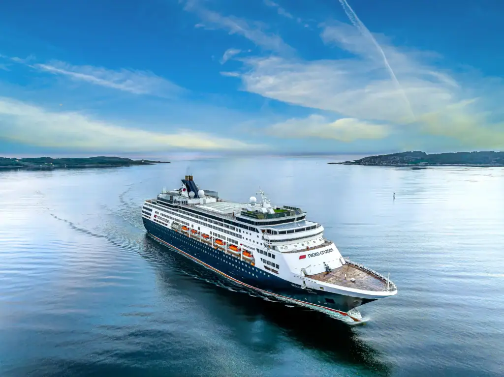 24-07-2022-Kristiansund_DJI_0022-DNG_DxO_DeepPRIME_24-07-2022-Kristiansund - Michis Kreuzfahrten large cruise ship gliding through calm blue water with low-lying islands in the distance under a clear sky. (nicko cruises vessel)