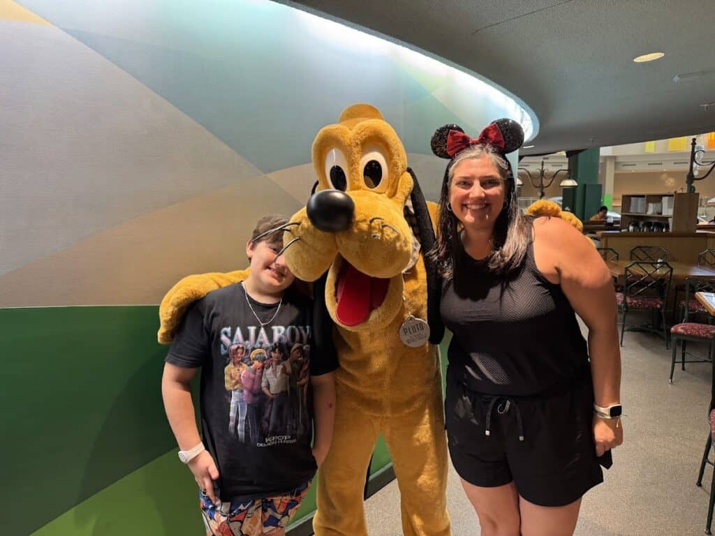 Family enjoying a fun Disney character encounter with Pluto at the theme park.