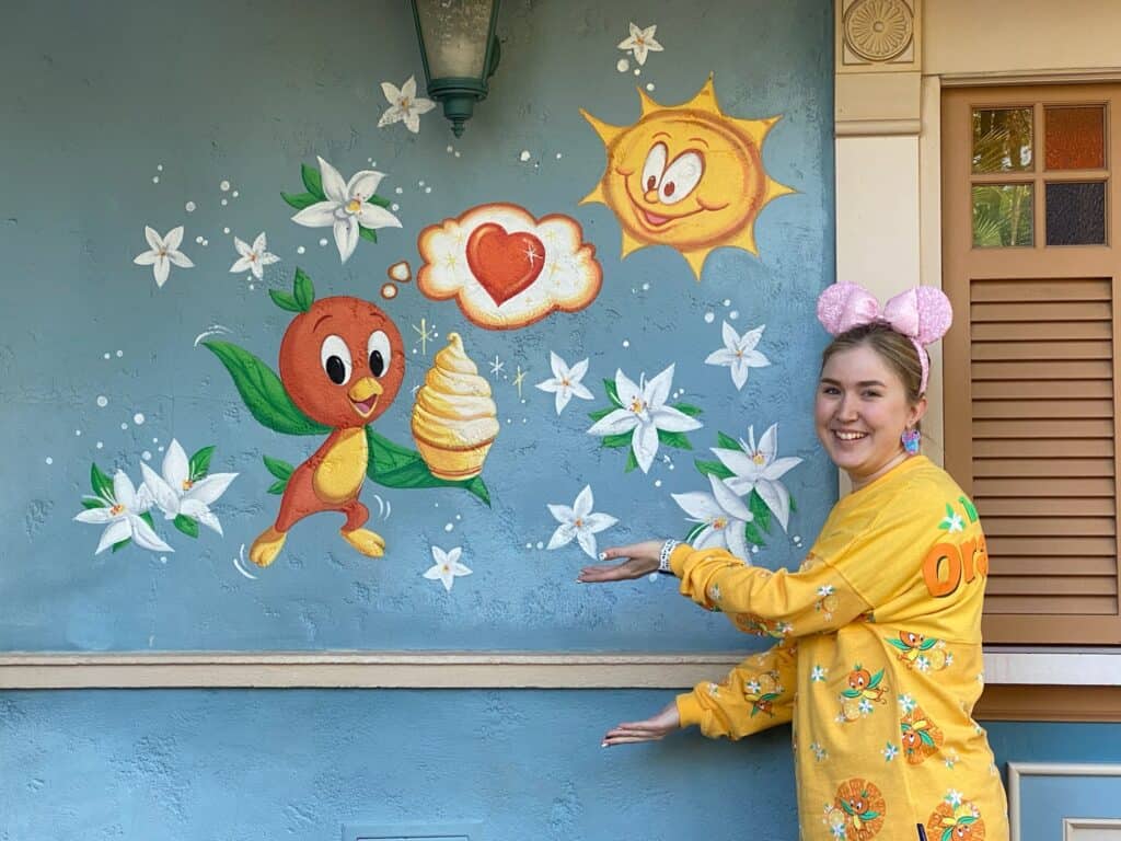 Colorful mural featuring a cheerful sun, smiling fruit character, and flowers at 407 Vacations.