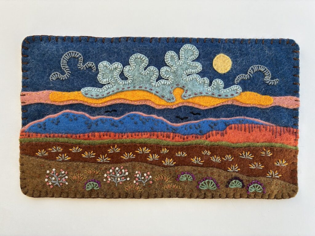 Embroidered artwork depicting clouds and plants