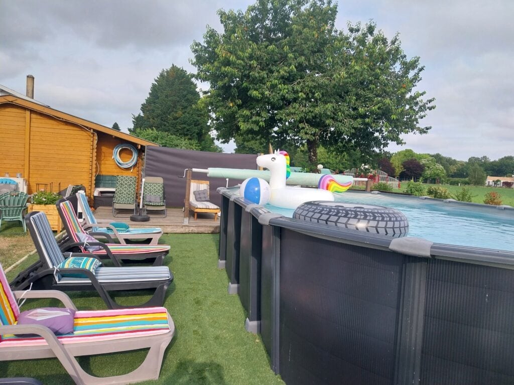 Terrasse en bois avec chaises longues colorées et piscine hors-sol décorée d'un motif licorne arc-en-ciel