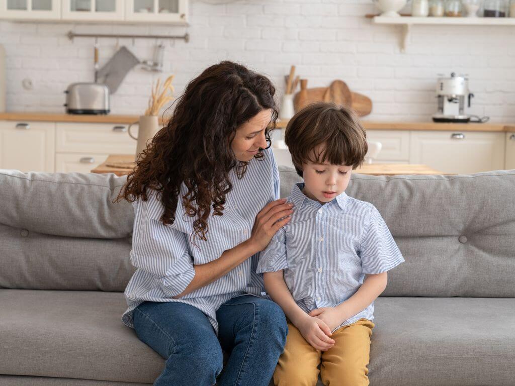 Mit dem Kind sprechen, Mutter auf Sofa mit Sohn, sie spricht eindringlich mit ihm