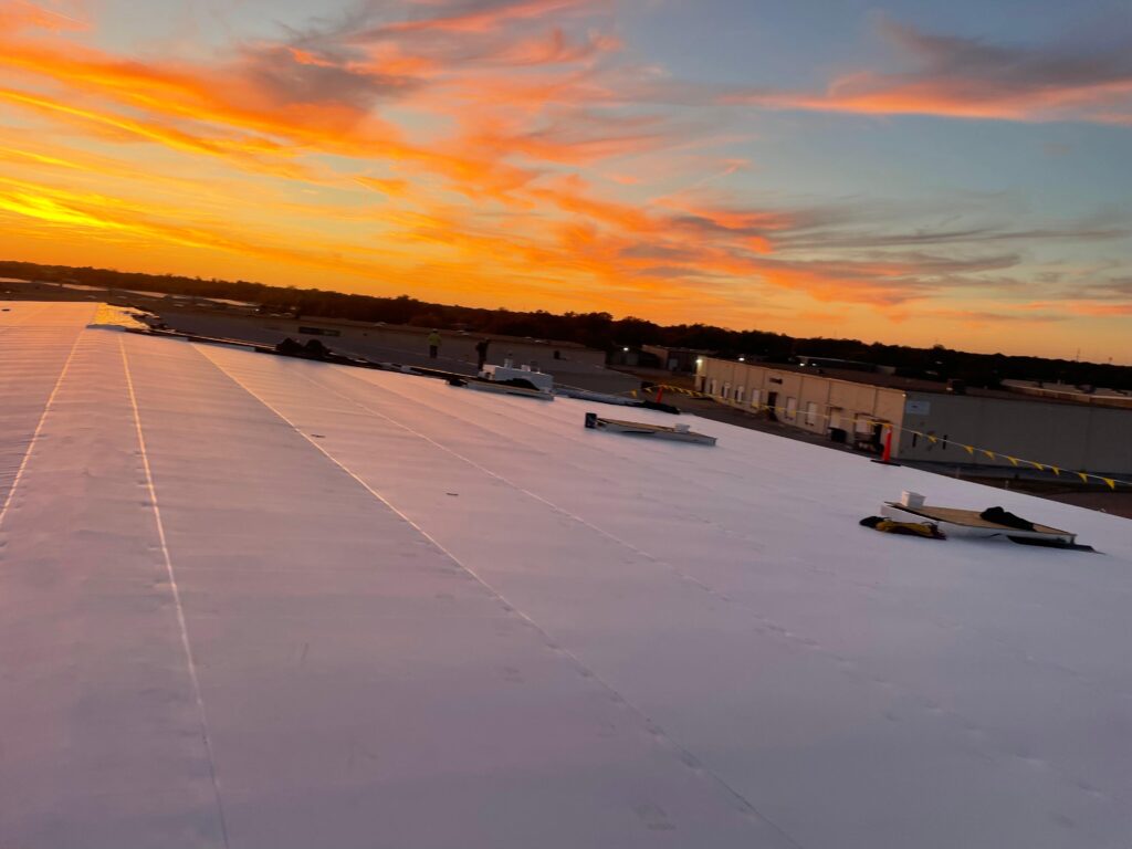 TPO commercial roof installation at sunset by JDCC Roofing in Weatherford, TX