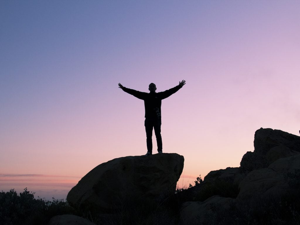 Standing on a rock celebrating a sunset