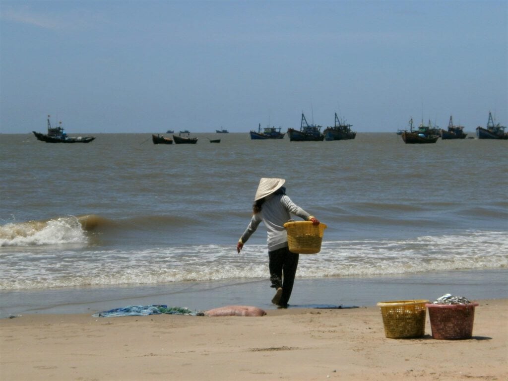 Woman working on Mui Ne beach, Vietnam. Vietnamese woman working on Mui Ne beach, with sea in the background.
