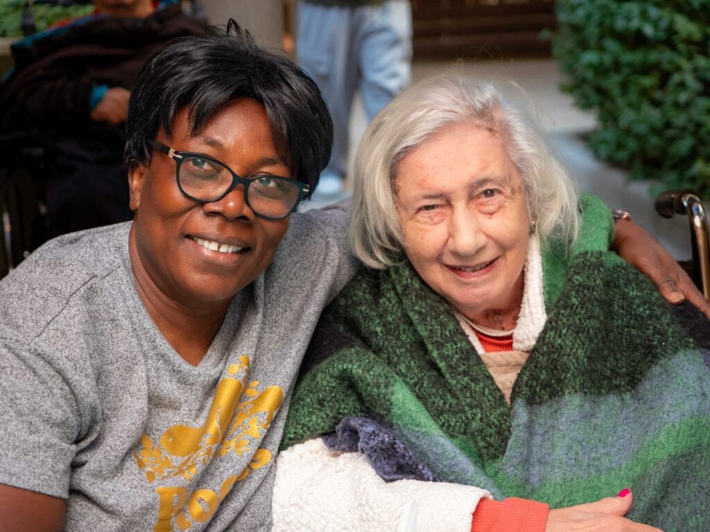 two women looking into the camera smiling and hugging
