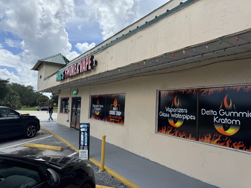 Mac's Smoke & Vape shop window graphics, advertising vaporizers, glass waterpipes, Delta gummies, and kratom.