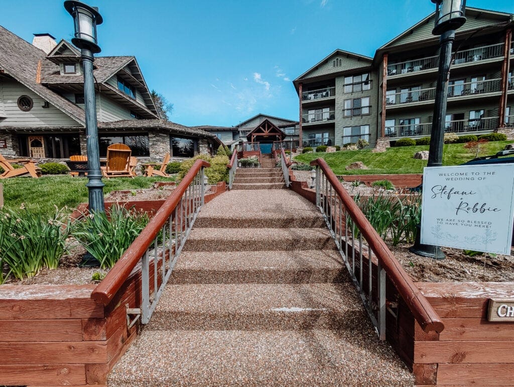 An exterior view of Chetola Lodge showing its Adirondack-style architecture, green lawns, and staircase leading to the entrance.