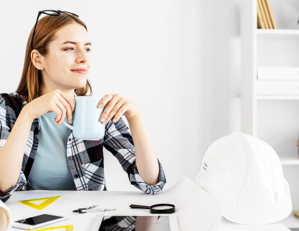 Architektin sitzt im Büro und trinkt Kaffee