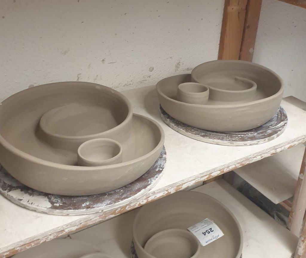 Spiralschüsseln im Töpferregal. Auf der Töpferscheibe frisch gedrehte Schüsseln, beim Trocknen in der Keramikwerkstatt. 