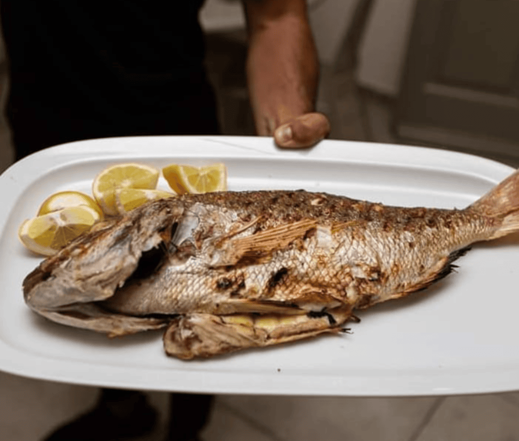 Whole grilled fish with lemon at Nautilus Mykonos — classic seafood main dish at top Mykonos fish restaurant.