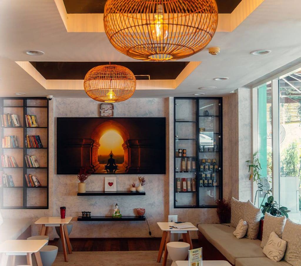 This image perfectly captures a modern, inviting sanctuary designed for both relaxation and quiet productivity. The warm lighting from the wicker pendants combined with the serene Buddha artwork creates a "zen-lounge" atmosphere that works well for a variety of professional platforms.