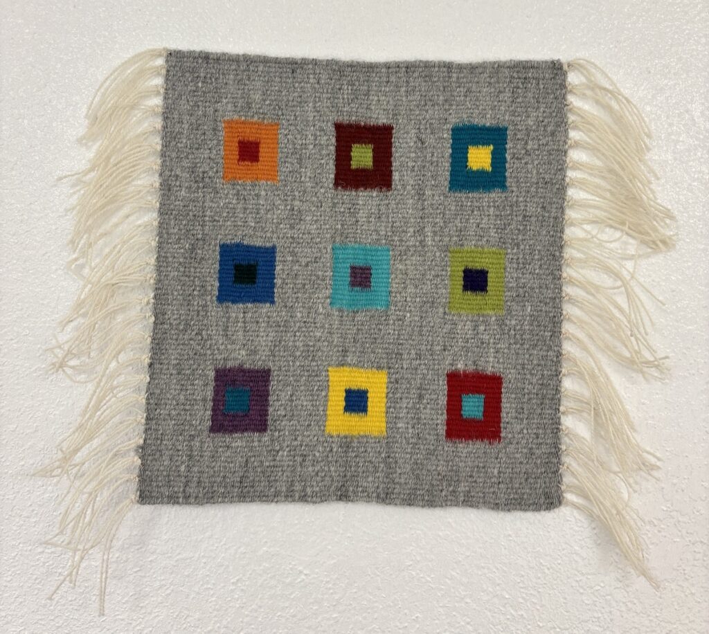 Gray tapestry with fringe and rainbow squares