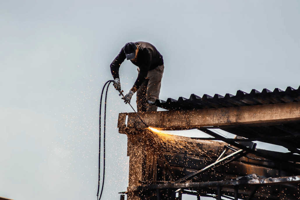 An experienced roofer performing maintenance on a red brick building. Reach out to us today and get your free estimate.