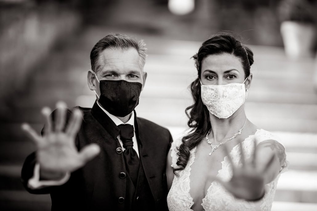 Braut & Bräutigam tragen einen Mundschutz und halten die Hände abwehrend Richtung Kamera Canon EOS R & RF 85mm