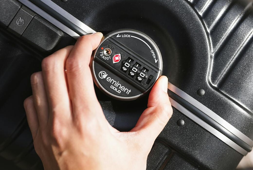 person hand holding knob of suitcase lock
