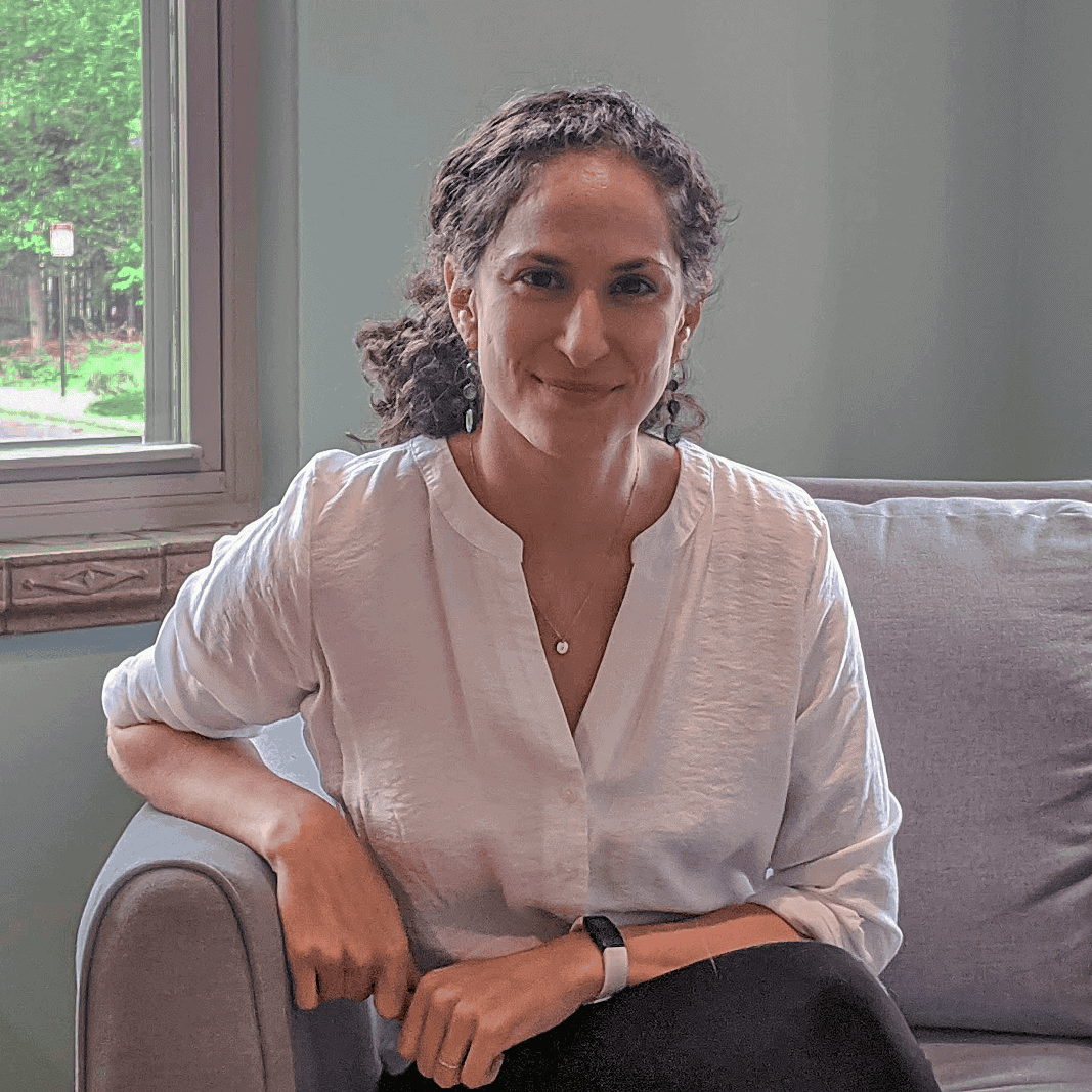 Skye D Ross sitting on a chair in natural light, offering a trauma focused and culturally affirming therapy environment.