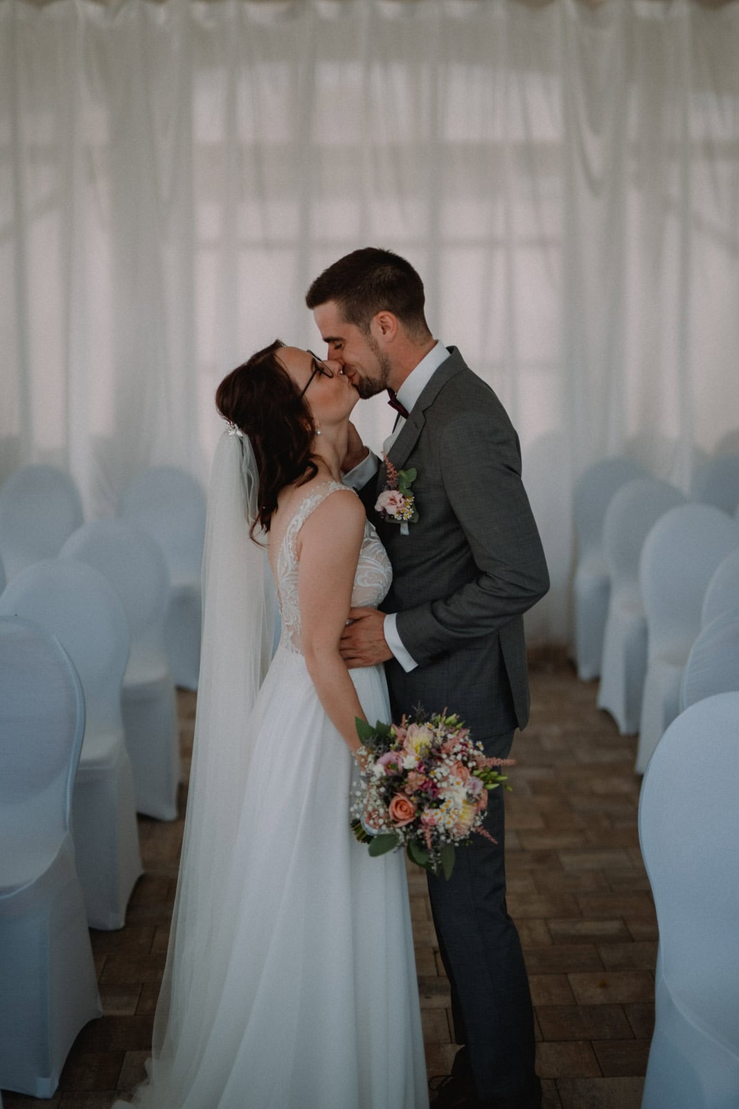 Brautpaar zwischen leeren Stuhlreihen