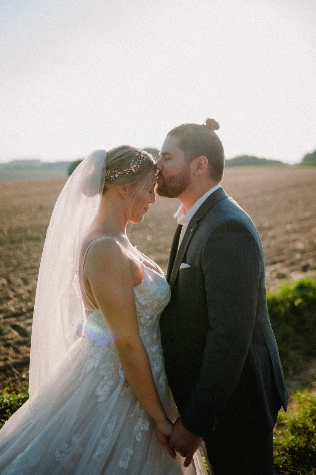 Bräutigam küsst seine Frau auf Stirn