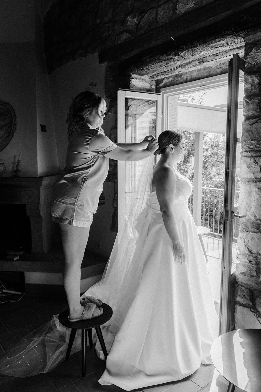 Maid of honour helping bride with dress details during getting ready photos