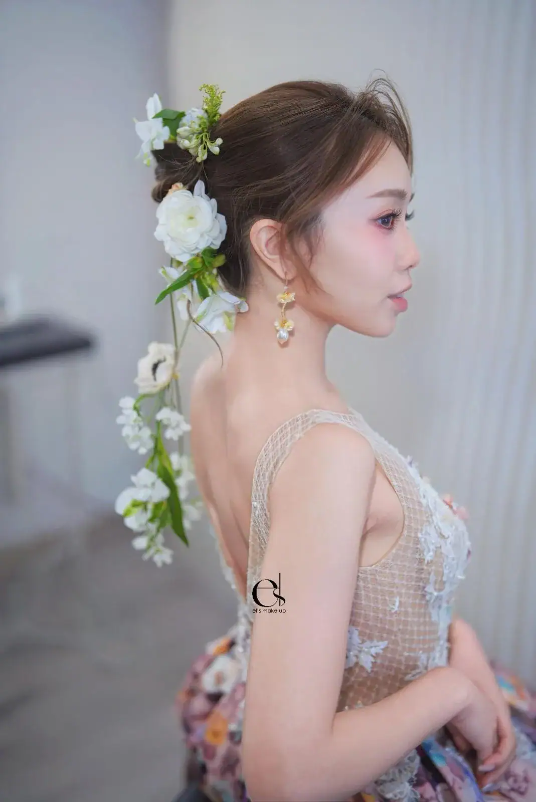 鮮花髮型設計班 7 側臉半身像:造型低髻插上黃蘭與綠色枝葉,模特兒側臉輪廓與精緻耳飾清晰呈現。