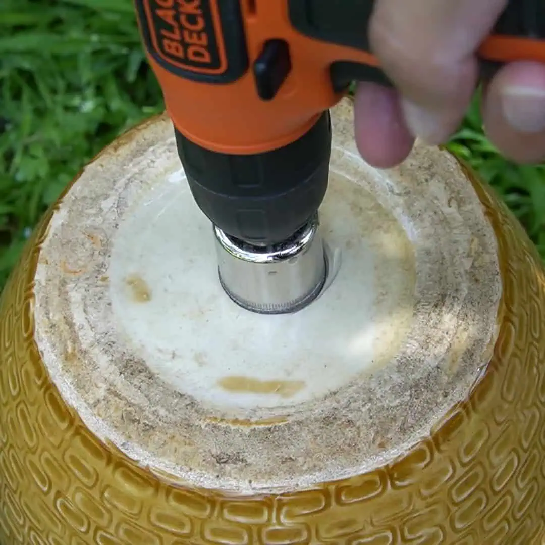 drilling a hole in a yellow ceramic pot 