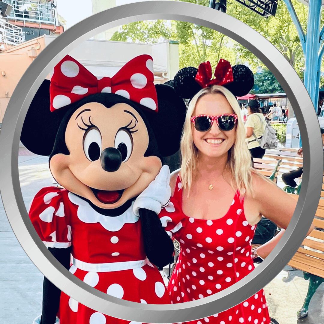 Minnie Mouse and Amy Morrison wearing matching red polka dot outfits at Disney park.