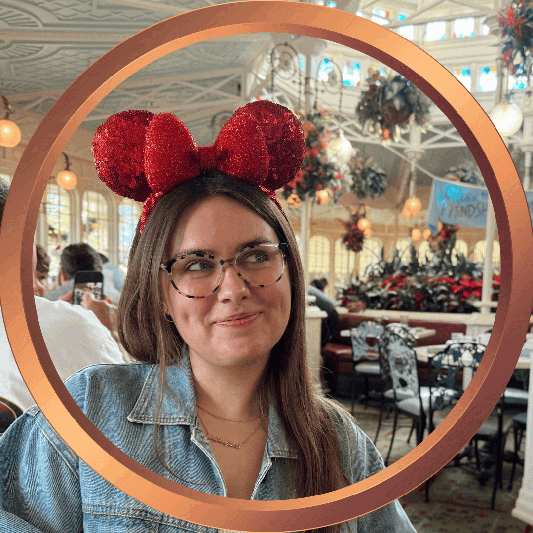 Girl with glasses and Minnie Mouse ears enjoying a Disney vacation celebration.