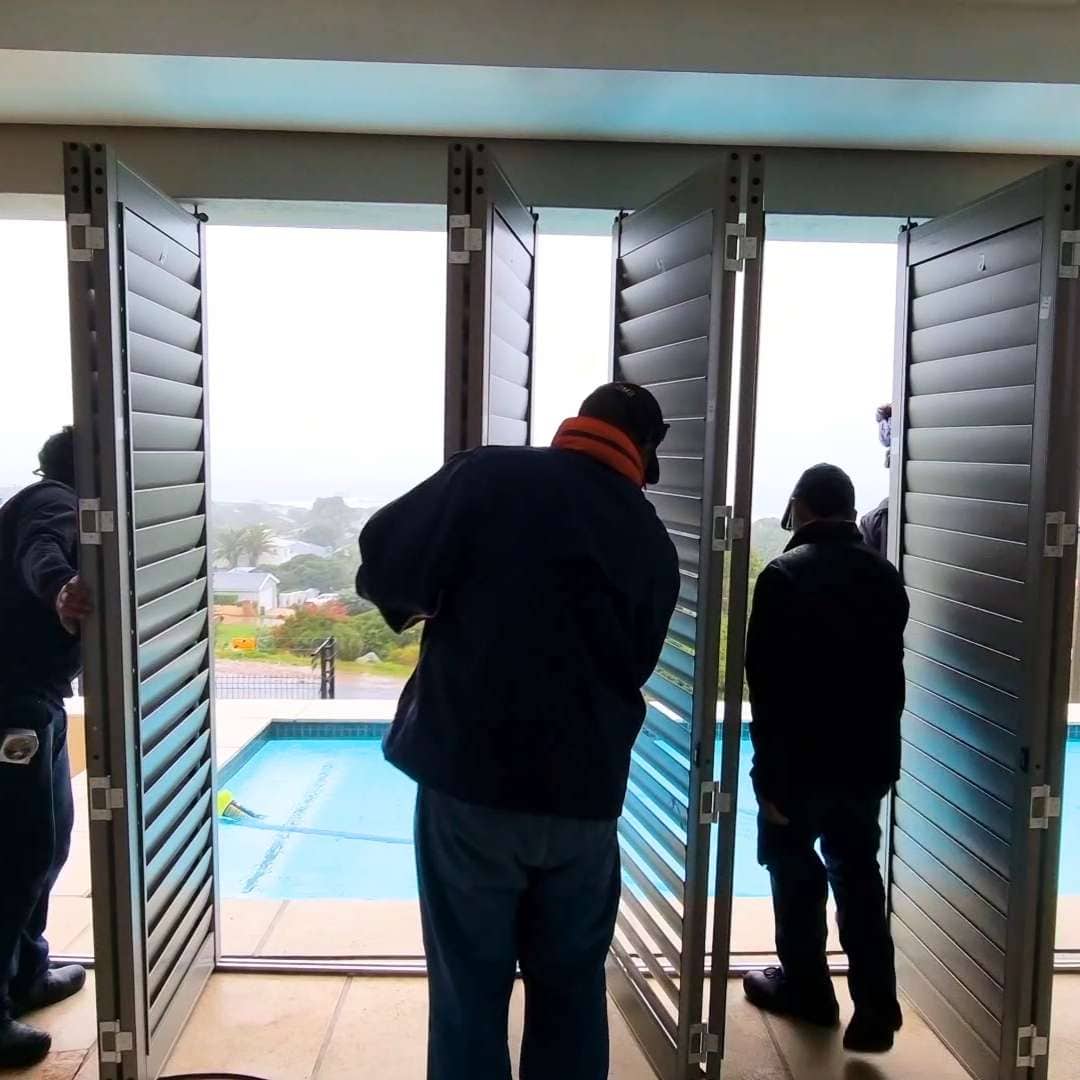 Team of professional installers fitting aluminium security shutters on a balcony, ensuring long-term peace of mind and expert installation.