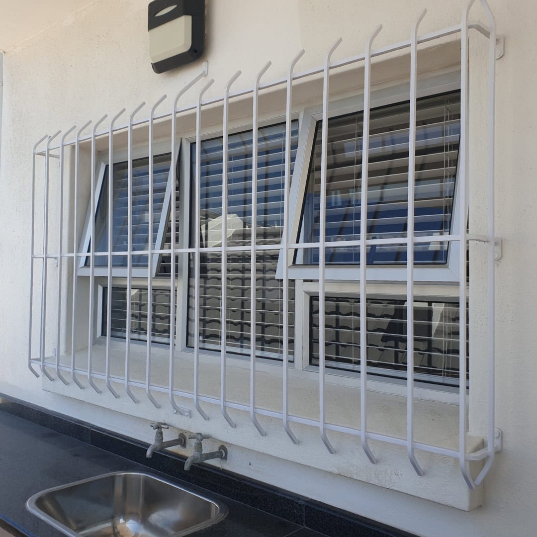 White spanish burglar bars installed outside of a kitchen window, overlooking an outside washing station.