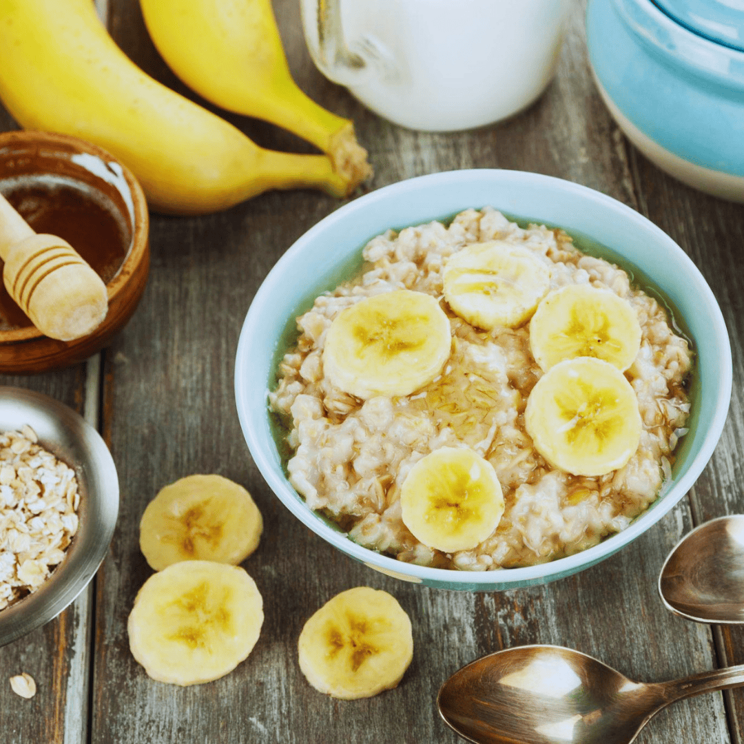 A blue bowl of cooked oats with slices of banana and honey