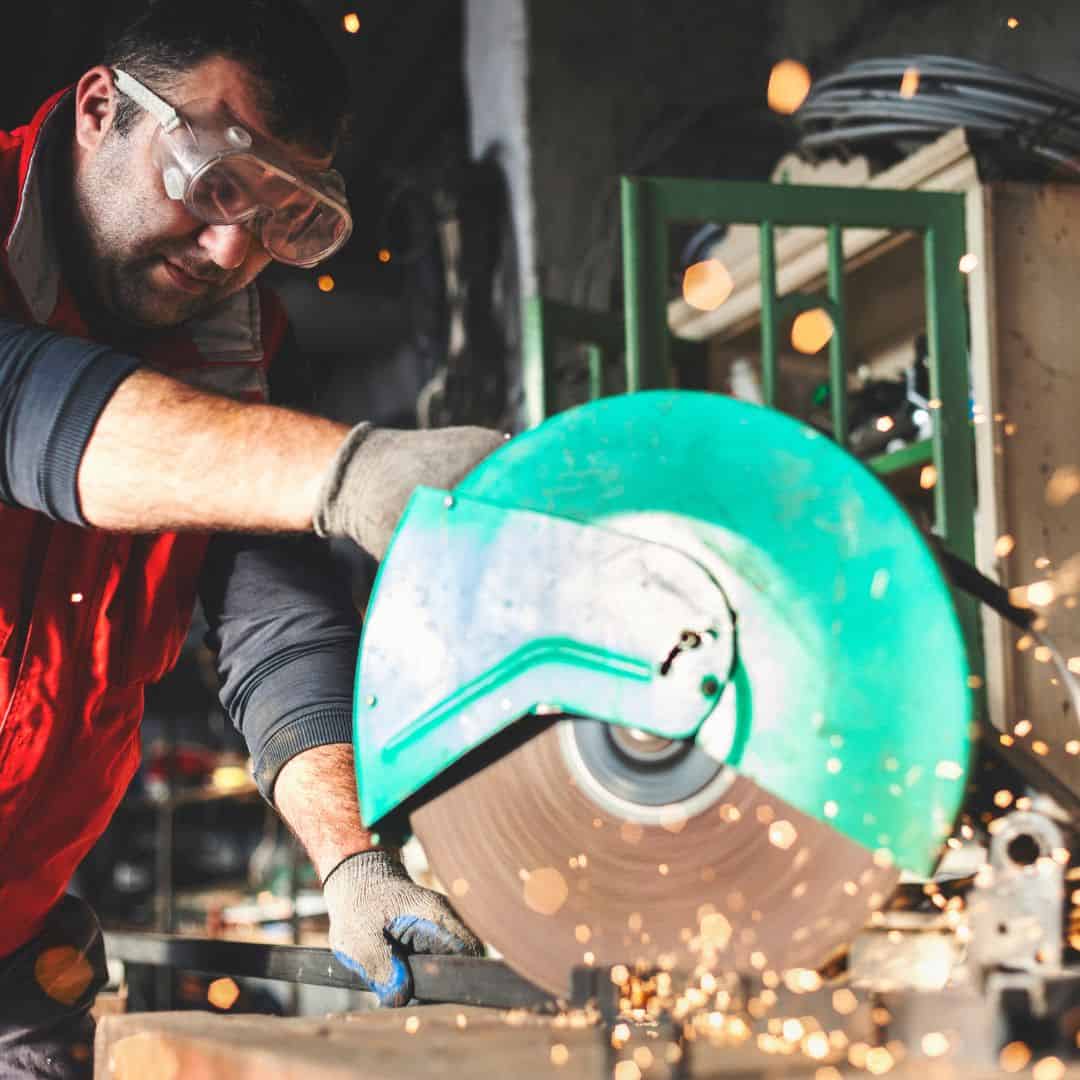 Worker in glasses cutting the metal bar