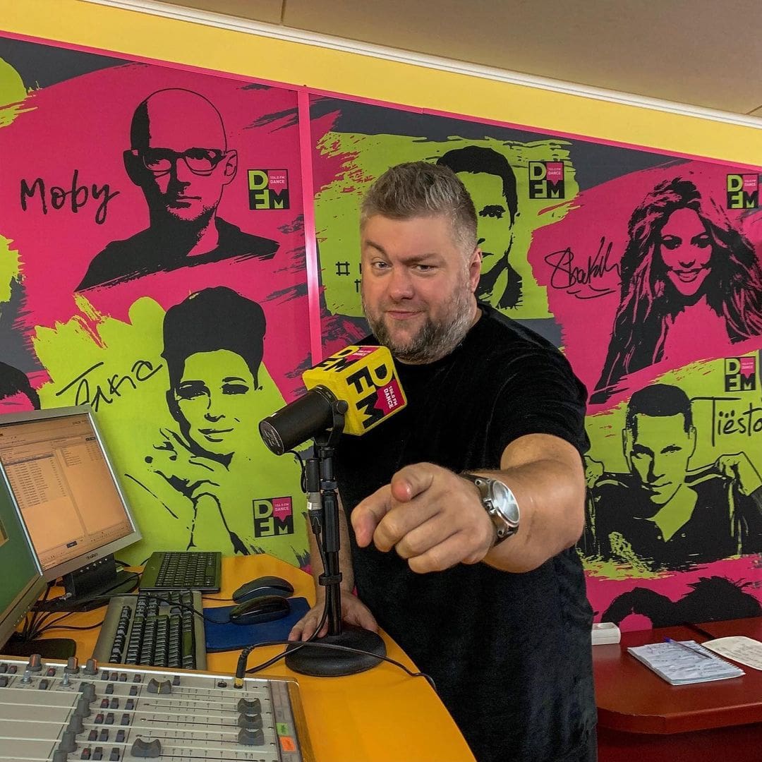 Радиоведущий в студии DFM с жёлтым поролоновым ветрозащитным чехлом с логотипом на микрофоне