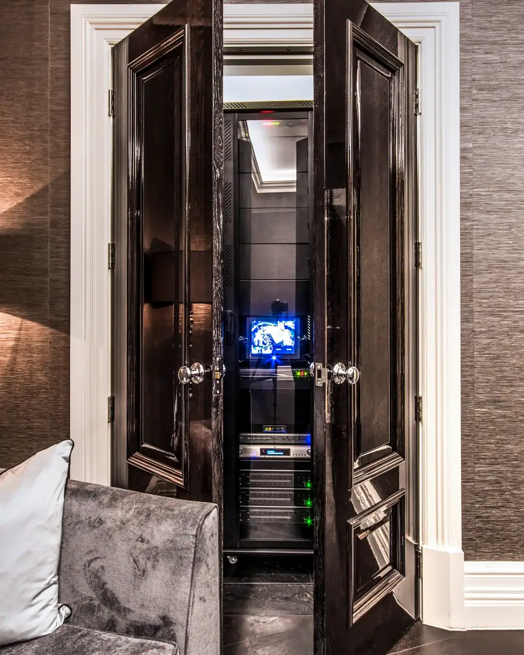 AV equipment rack inside a cupboard behind black panelled doors