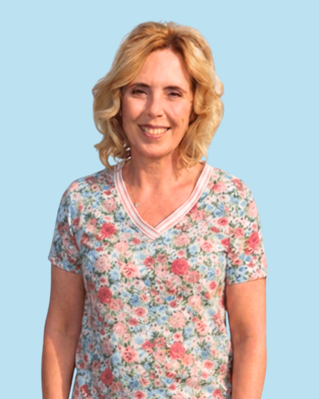 Smiling woman with blonde hair in floral shirt, representing our team.