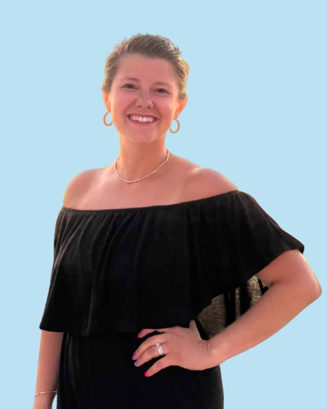 Smiling woman in black off-shoulder dress with jewelry.