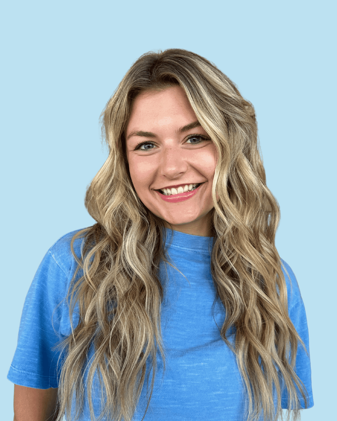 Smiling woman with long blonde hair in a blue t-shirt, representing our team.