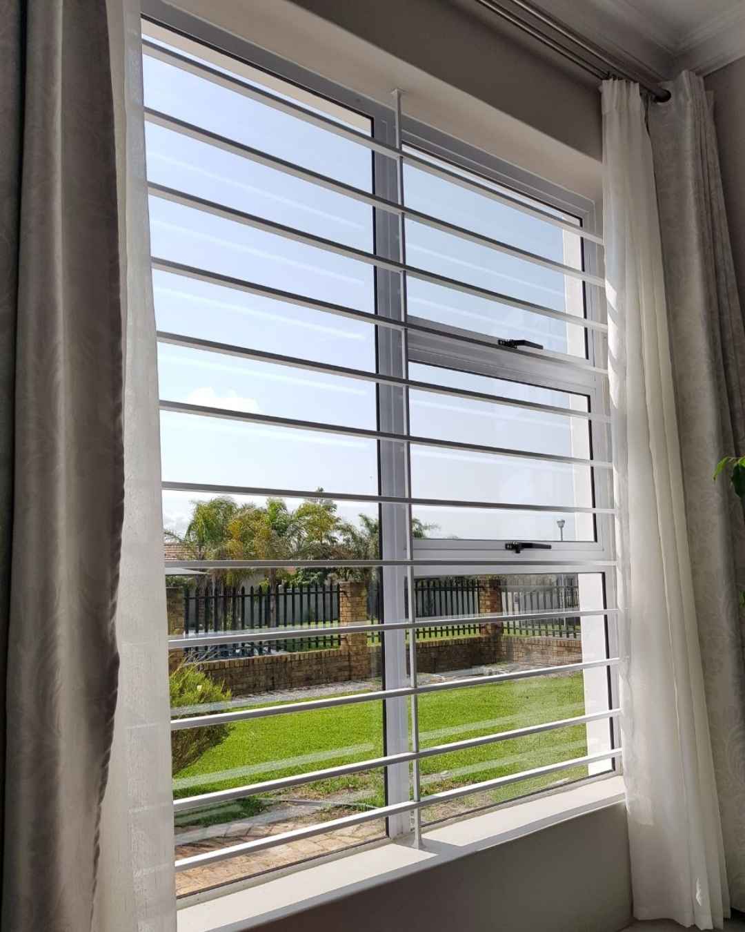 Horizontal steel burglar bars mounted on a window, enhancing home security while maintaining visibility and airflow.