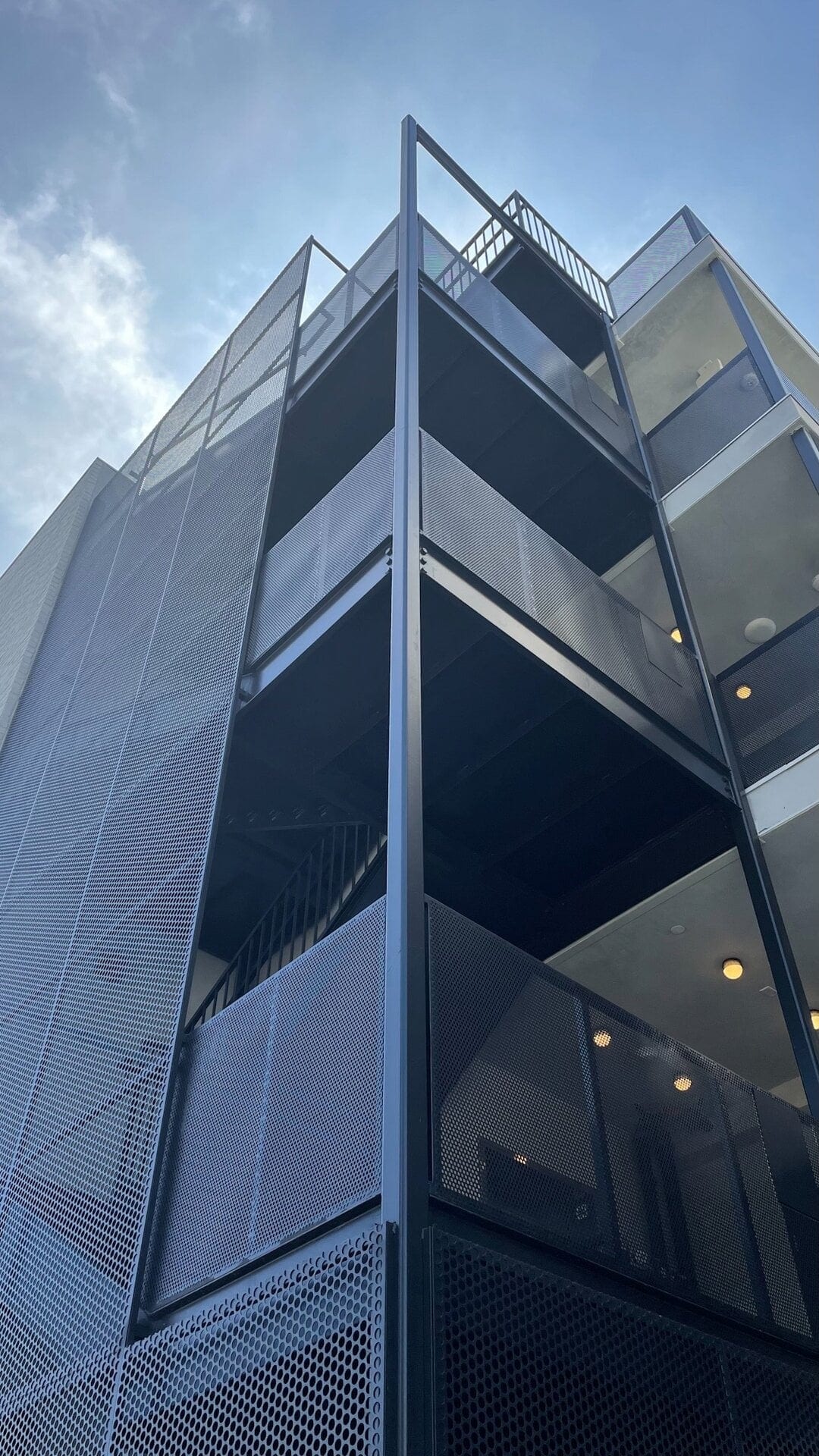 Modern multi-story residential building with black metal facades and glass balconies.