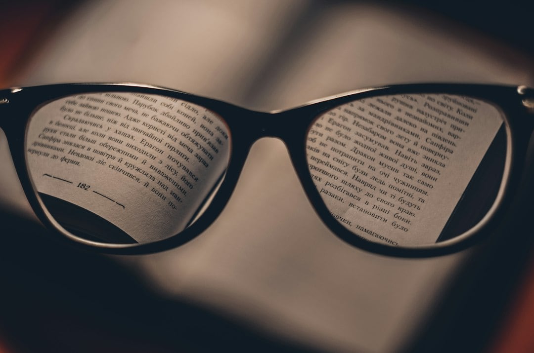Anteojos frente a un libro abierto, con el texto enfocado a través de las lentes.