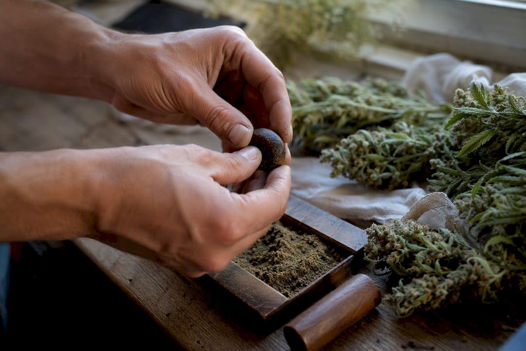 Mains pressant du haschich artisanal frais sur du bois