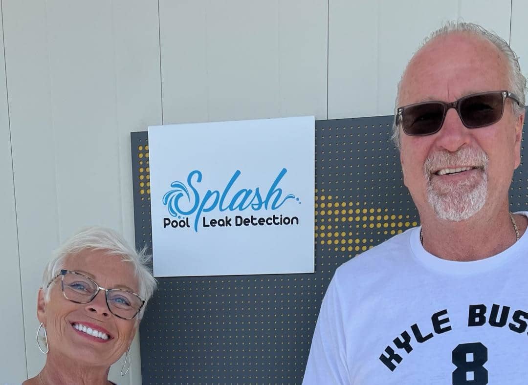 Two people smiling beside a Splash Pool Leak Detection sign