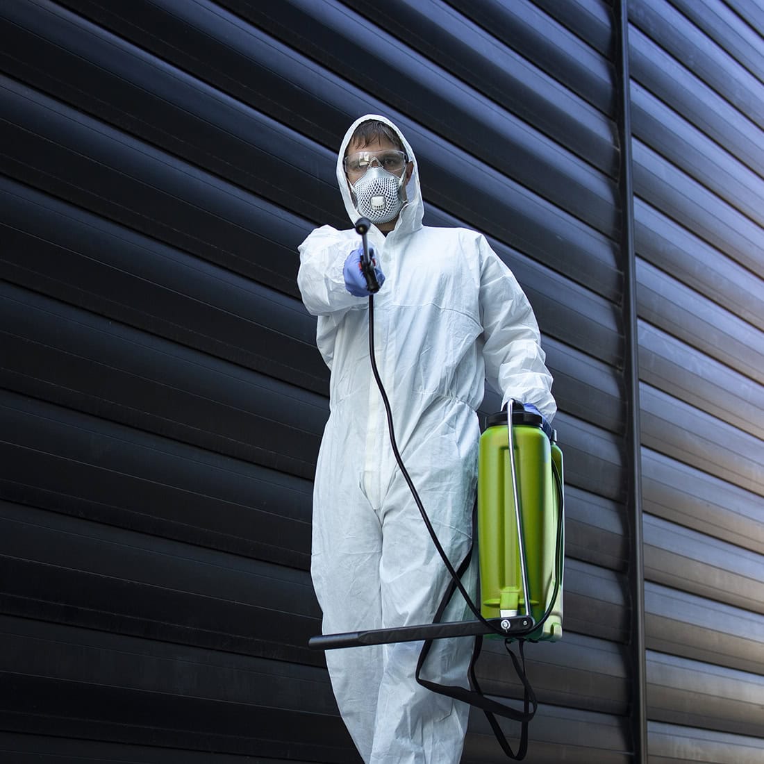 Person in white chemical protection suit doing disinfection and