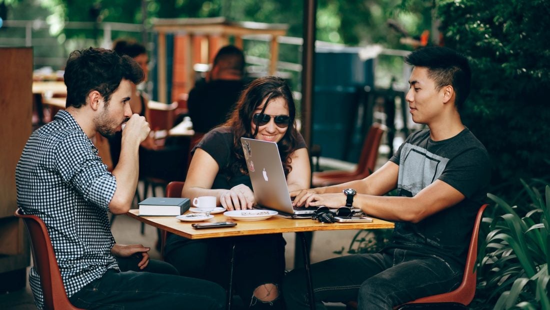 Three Millenials are sitting at a table in the restaurant.