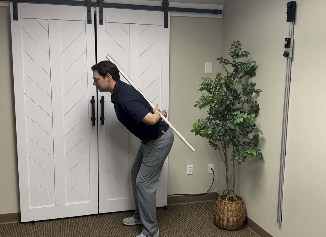 Dr. Henry demonstrating a hip-hinge exercise with a dowel