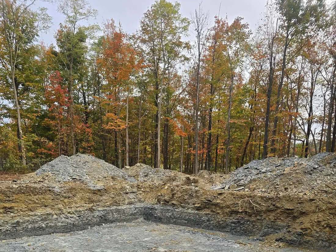 Excavation in Jamestown, NY Foundation excavation near Jamestown, NY, cut down to shale with clean square walls and spoil piled around it, autumn tree line beyond