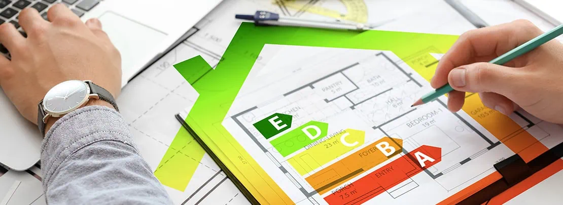 Architekt arbeitet am Energieeffizienzplan eines Hauses mit farblich gekennzeichnetem Energieausweis von A bis E.