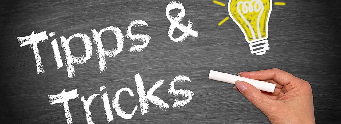 Tafel mit der Aufschrift „Tipps & Tricks“ und gezeichneter Glühbirne. Symbolbild für Tipps und Tricks gegen die Kälte